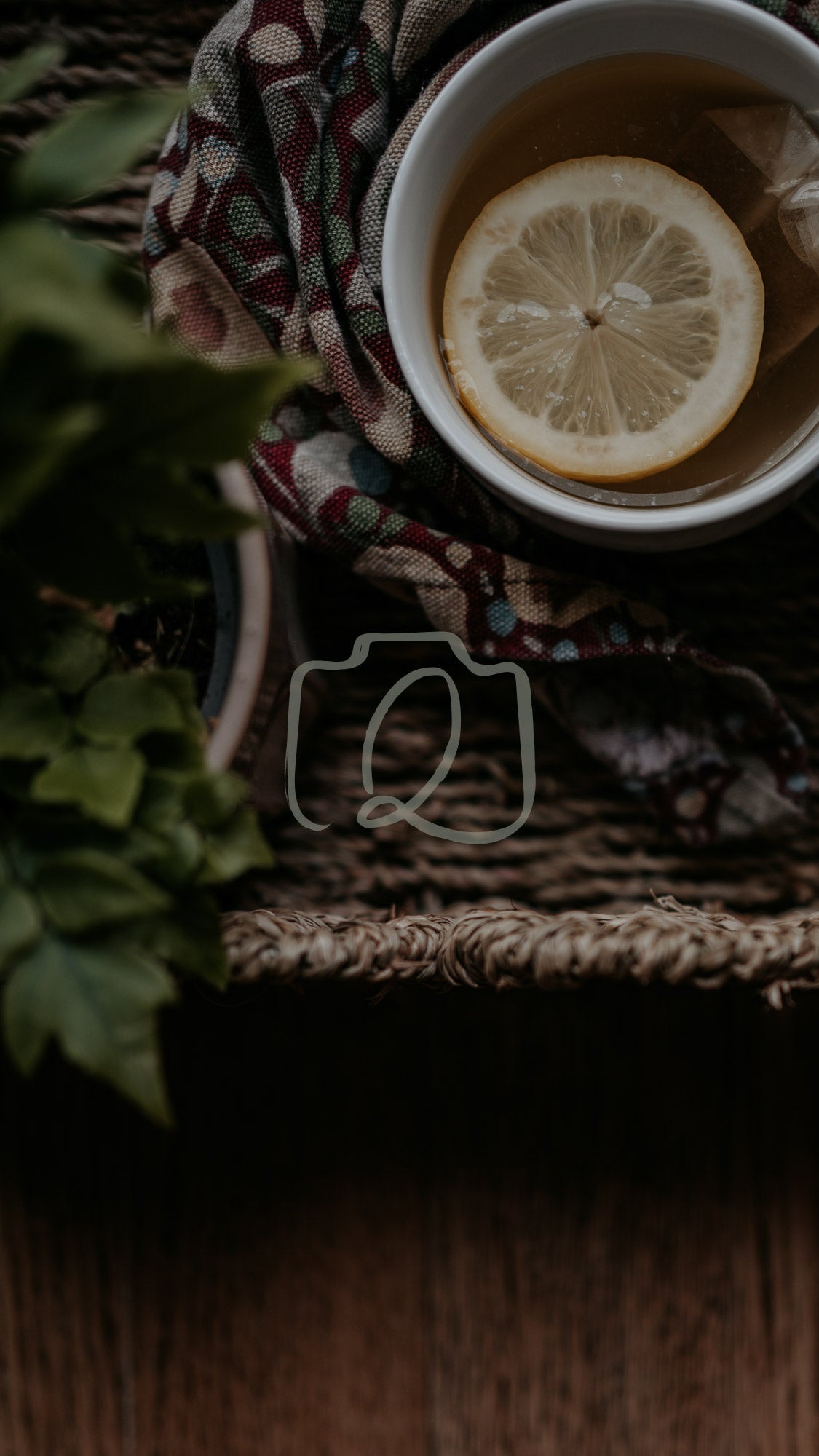 Cup of lemon tea on woven tray with patterned cloth and green foliage in warm rustic scene